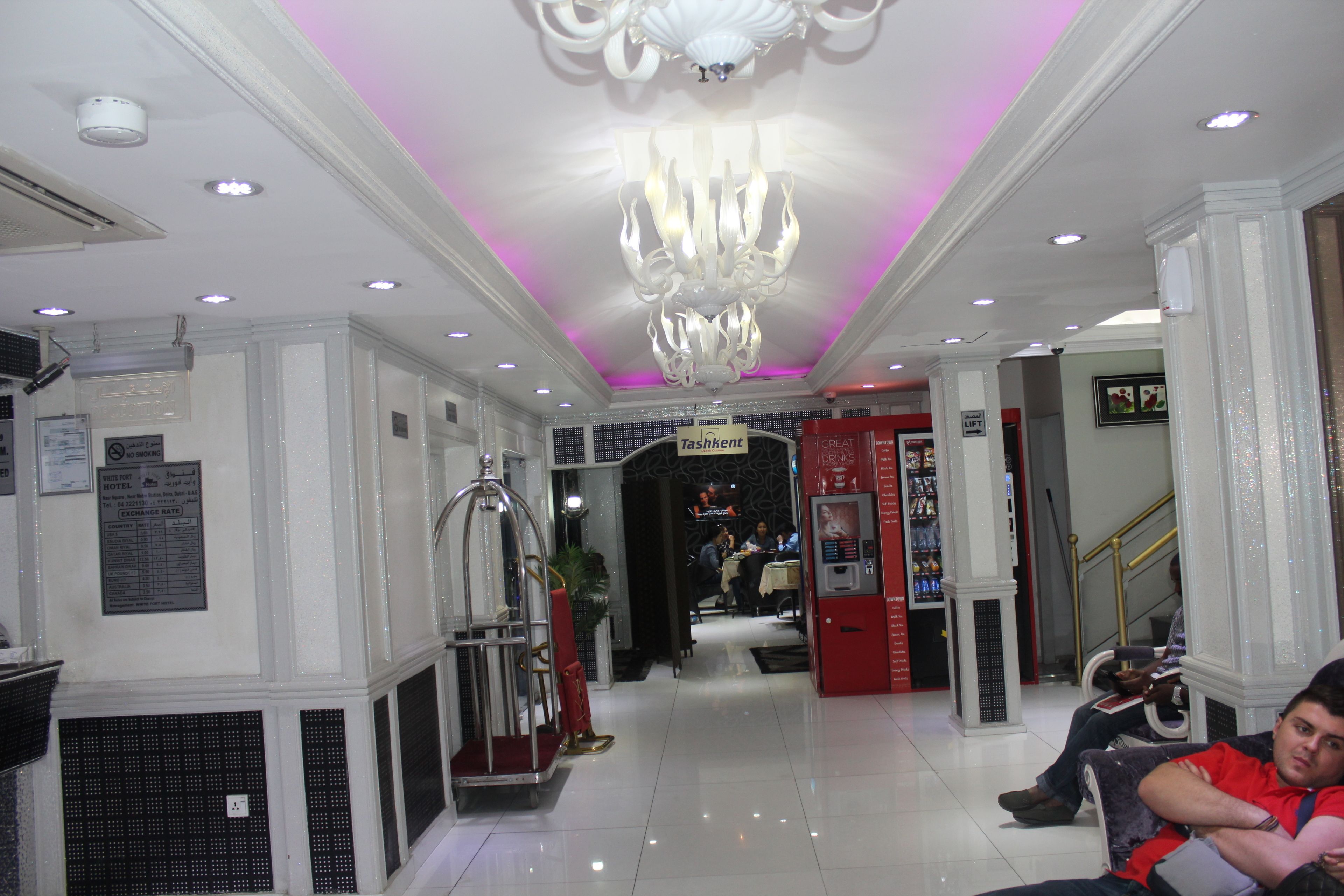 A hotel lobby with a chandelier, a reception desk, and a seating area.