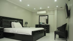 A modern bedroom with a large bed, a dresser, a chair, and a TV. - White Fort Hotel (Dubai)