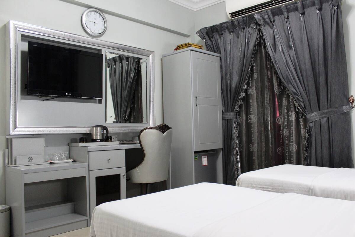 A hotel room with a bed, a desk with a mirror, a television, and a wardrobe.