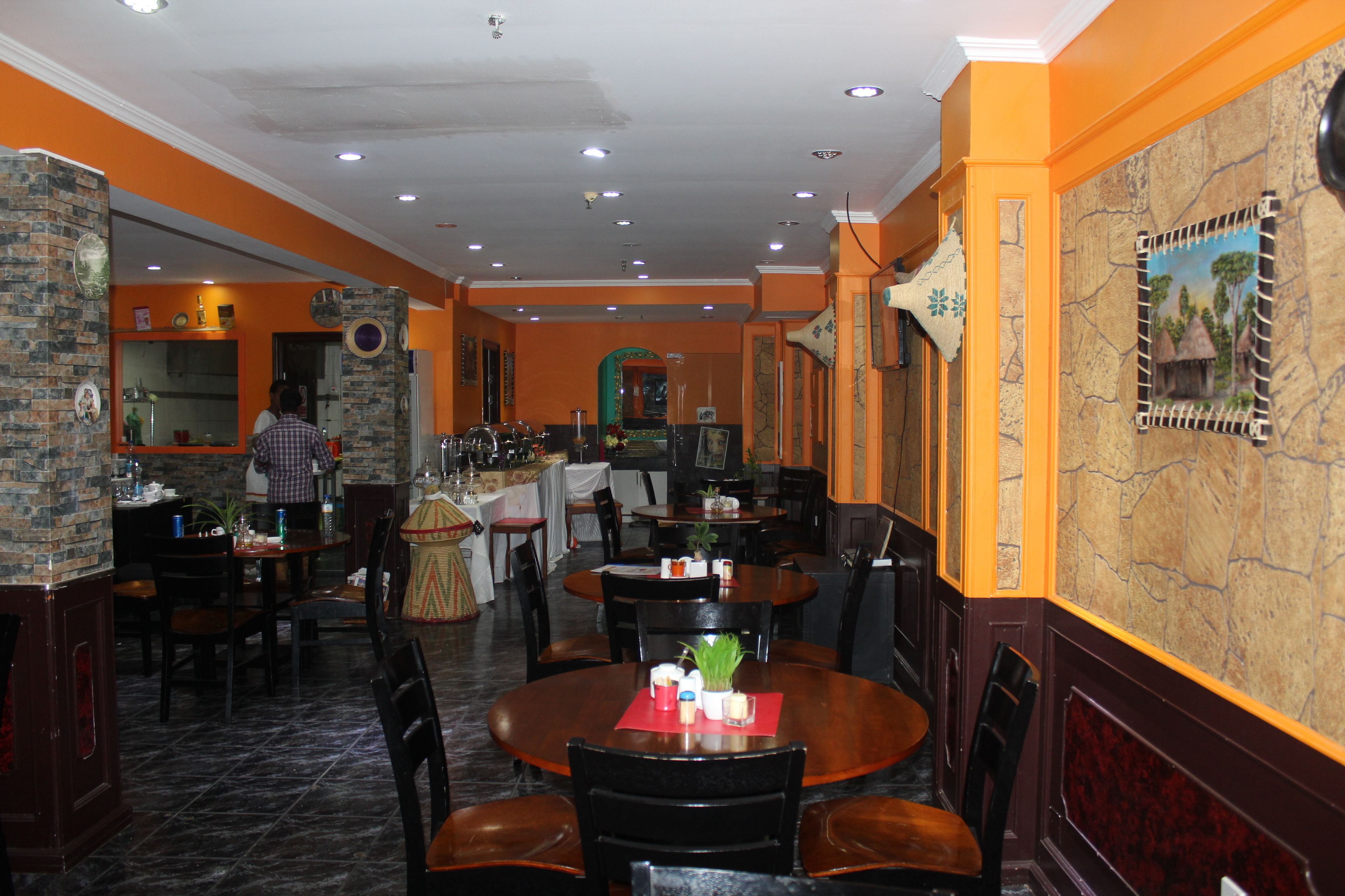 A restaurant with round tables, chairs, and a bar area.