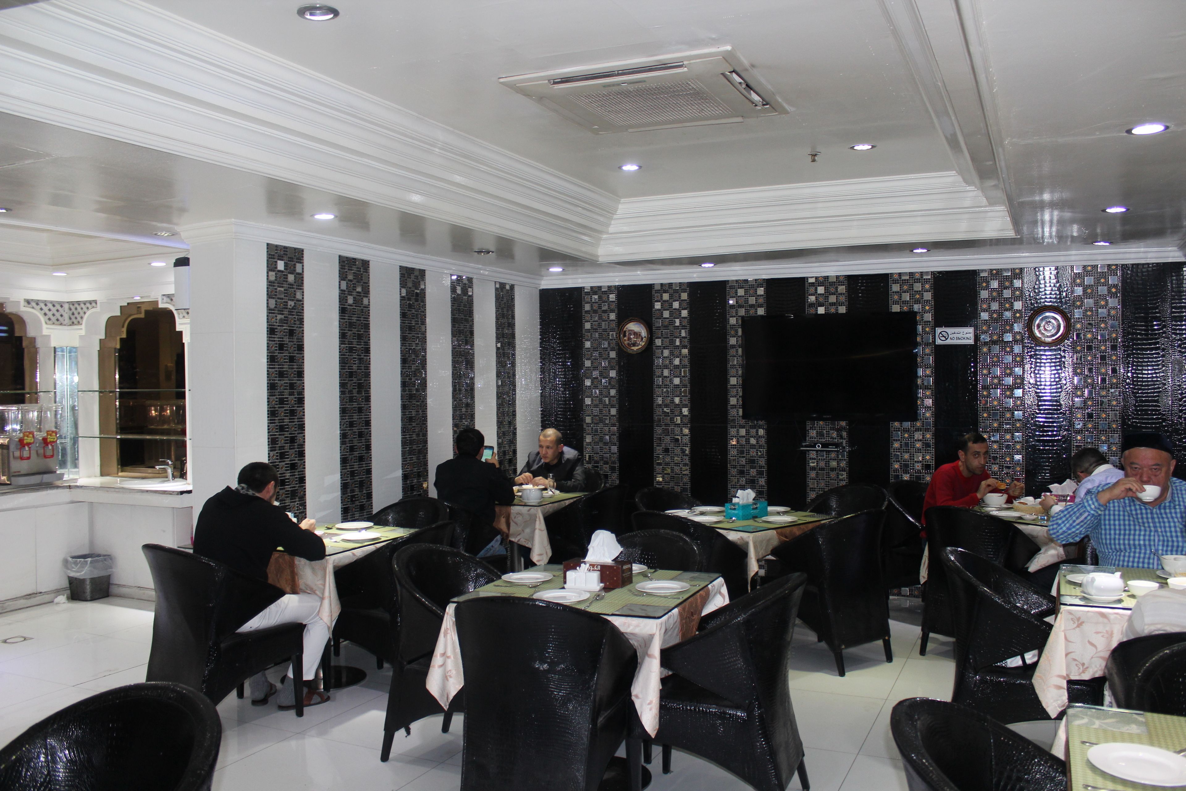 A restaurant with black chairs, white tables, and tiled walls.