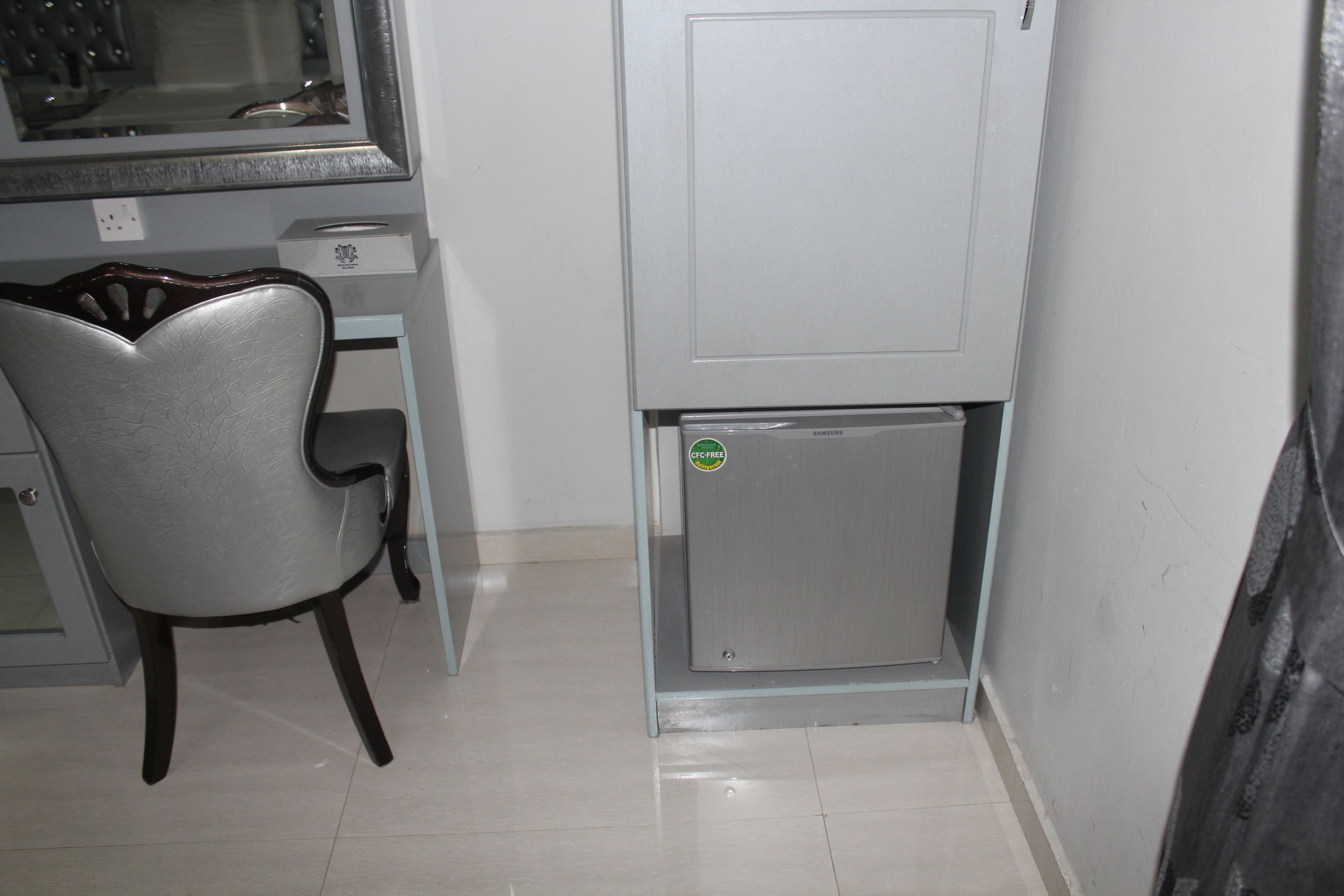 A small kitchenette with a refrigerator, a microwave, and a chair.