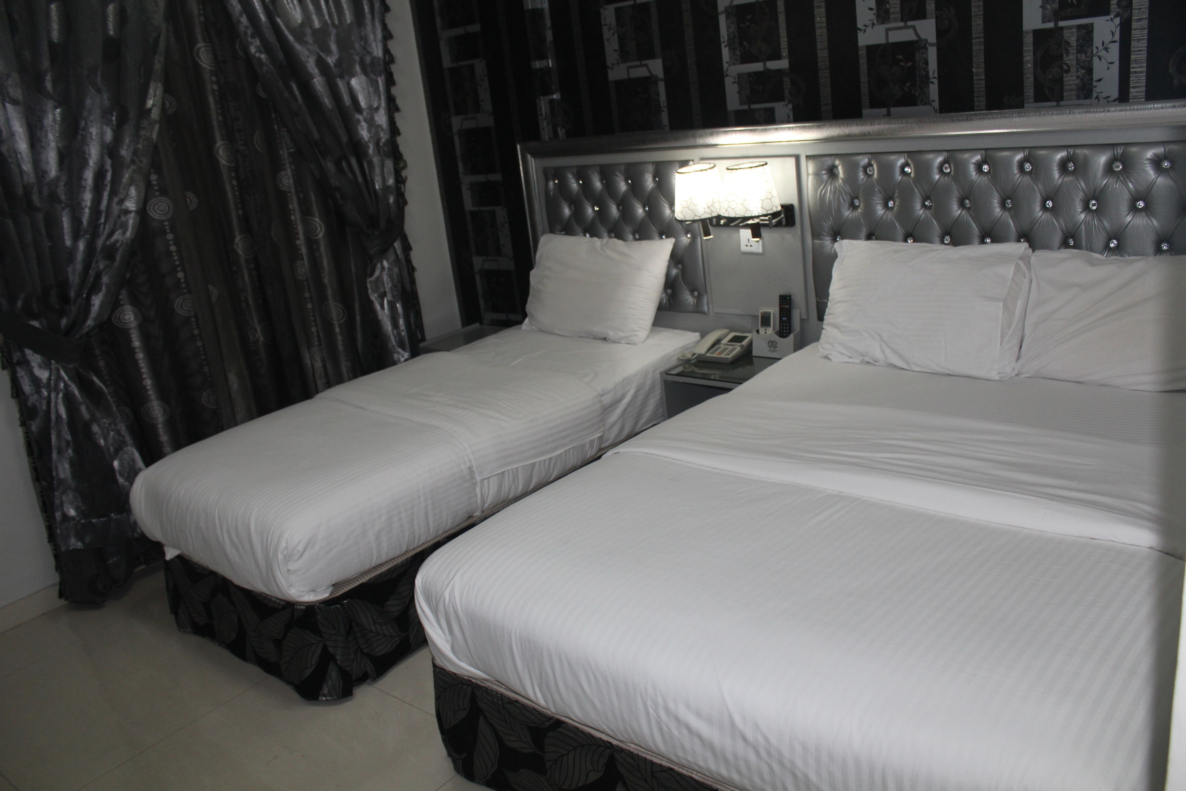 Une chambre d’hôtel avec deux lits simples, une table de chevet avec une lampe et un téléphone.
