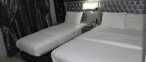 Une chambre d’hôtel avec deux lits simples, une table de chevet avec une lampe et un téléphone.
