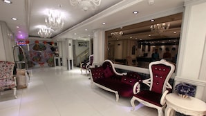 A lobby with a white tiled floor, ornate white furniture, and a chandelier. - White Fort Hotel (Dubai)