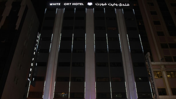 The exterior of the White Fort Hotel with illuminated signage and a modern architectural design. - White Fort Hotel (Dubai)