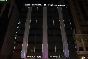 The exterior of the White Fort Hotel with illuminated signage and a modern architectural design. - White Fort Hotel (Dubai)