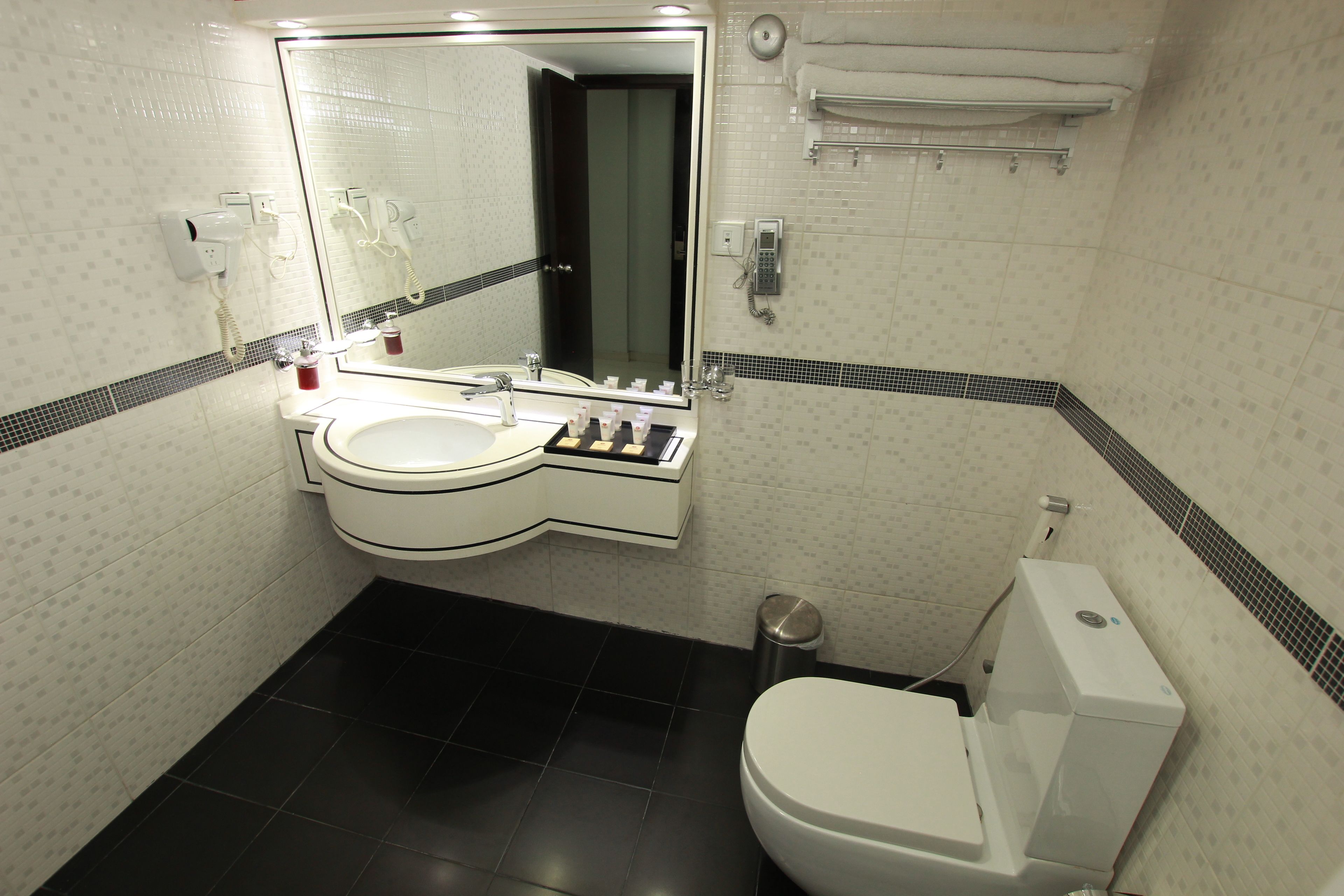 A modern bathroom with a white sink, a large mirror, a toilet, and a shower area.