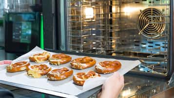 Een persoon houdt een schaal versgebakken pretzels voor een oven.