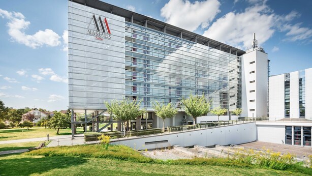 A modern building with a glass facade, a prominent logo, and a staircase leading to an upper level.