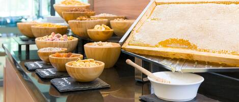 A buffet with various food items in wooden bowls and a large honeycomb display.