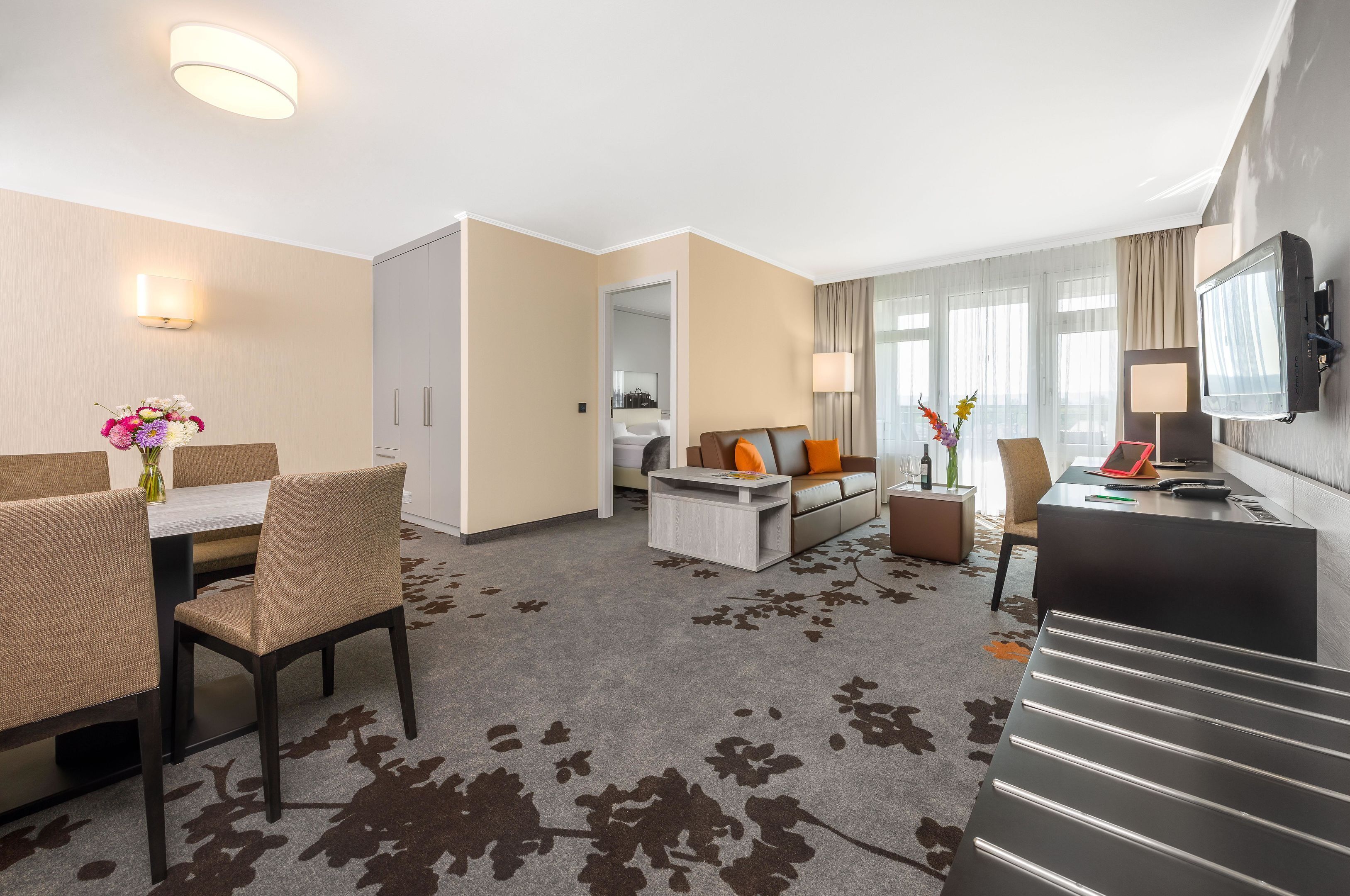 Una habitación de hotel con comedor, sofá, televisor y escalera.