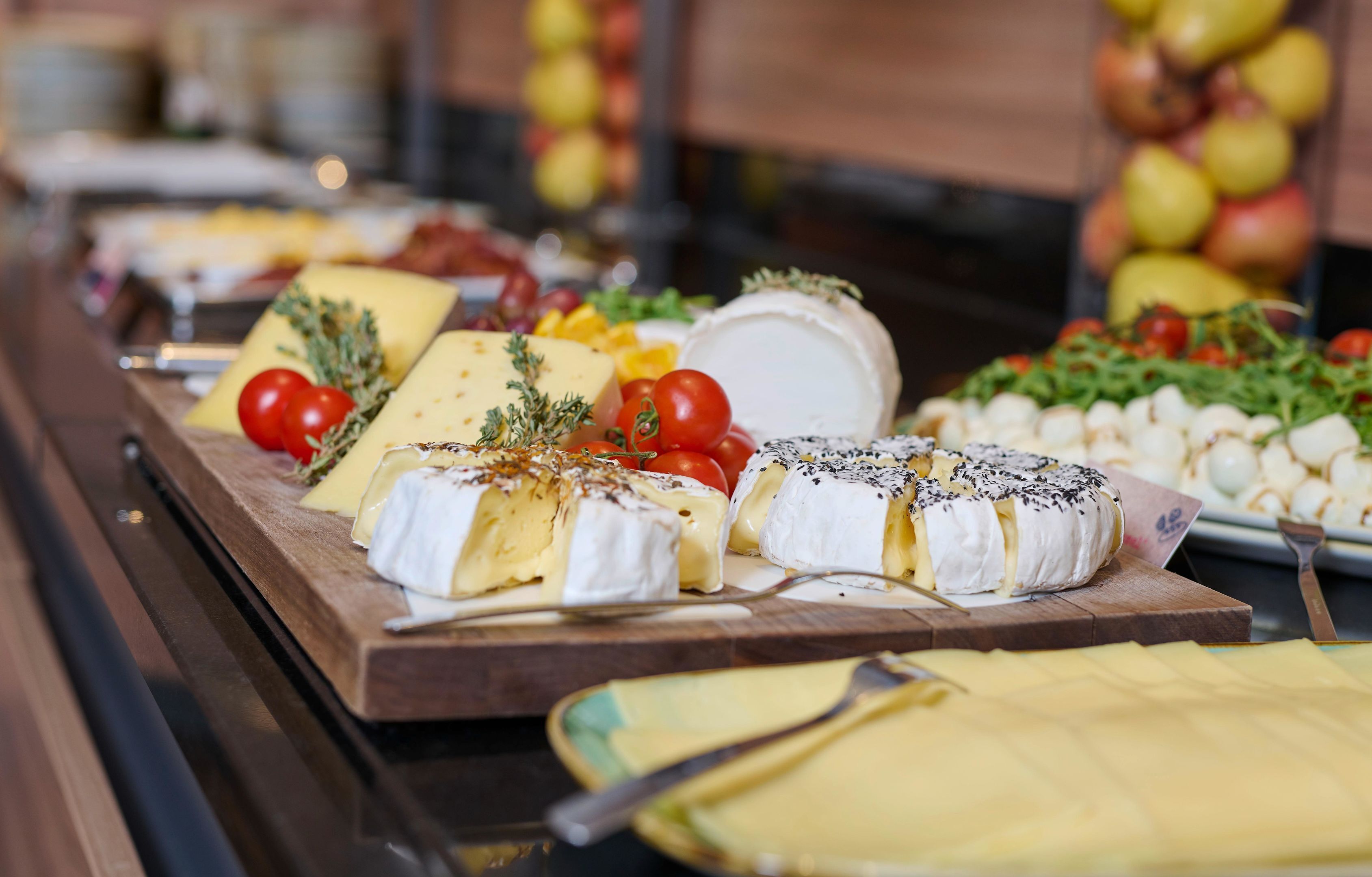 A buffet table with various cheeses and fruits.