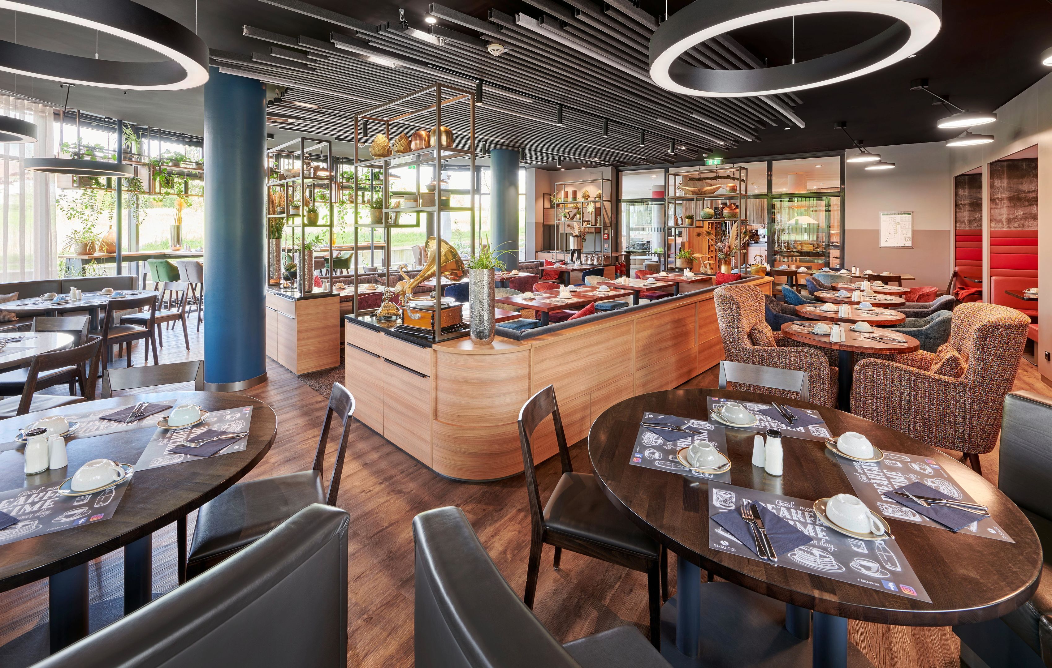 Un interior de restaurante moderno con mesas redondas, asientos de bar y una barra central.