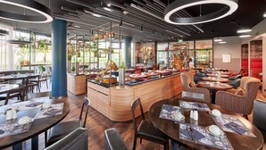 A modern restaurant interior with round tables, bar seating, and a central counter.