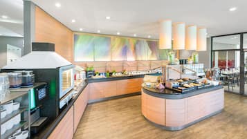 Una barra de desayuno moderna con diversas opciones de comida, una máquina de café y vista al área de comedor.