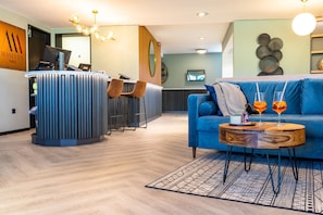 A modern hotel lobby with a reception desk, seating area, and a blue sofa with drinks. - MASEVEN Stuttgart SI-Centrum (ehem. SI-SUITES) (Stuttgart)