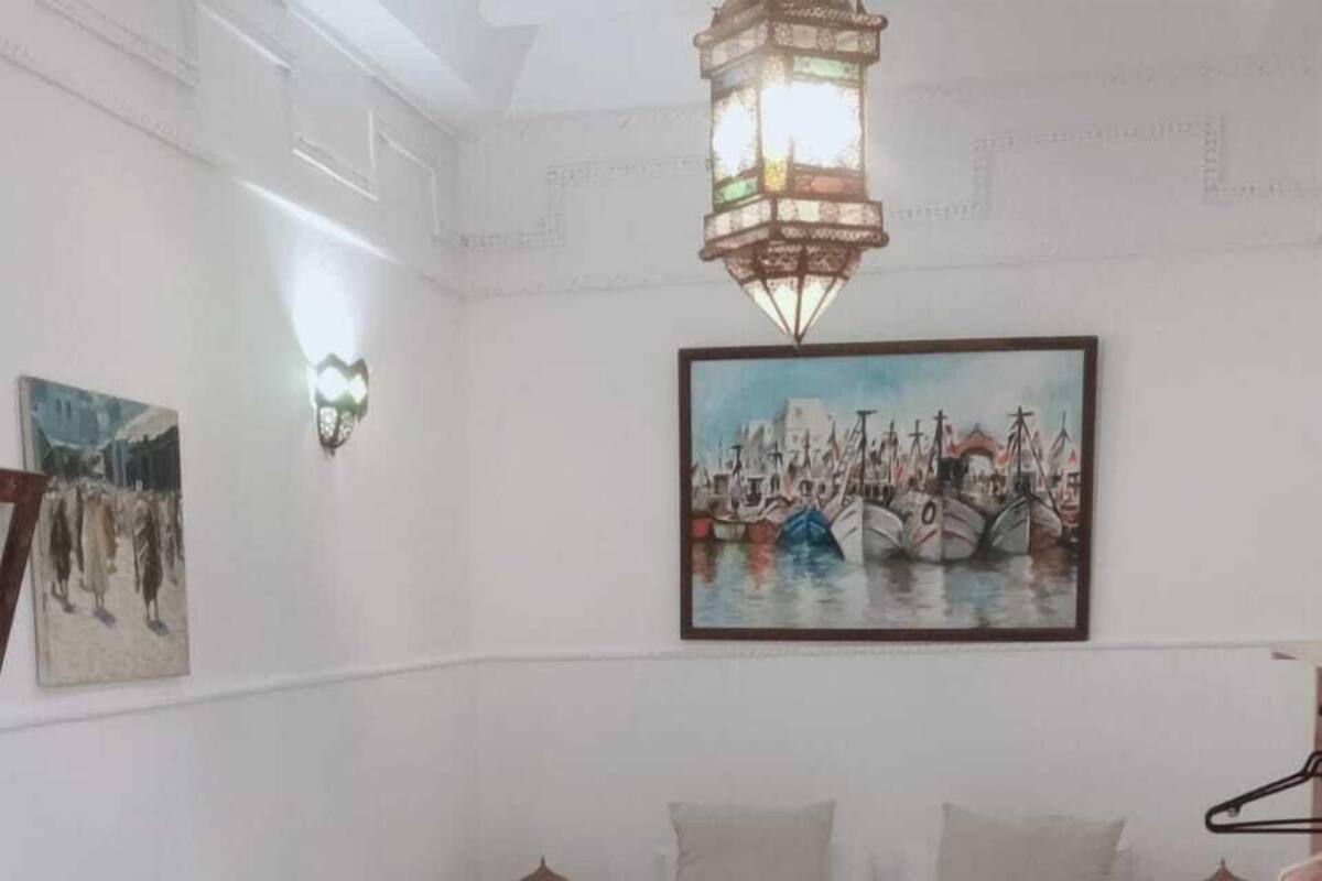 A bedroom with a bed, a painting, and a chandelier.