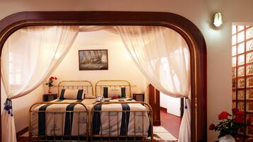 A bedroom with two beds, a painting on the wall, and a window with curtains.