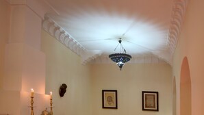 A dining area with a fireplace, table set with chairs, and a chandelier. - Dar Loulema (Essaouira)