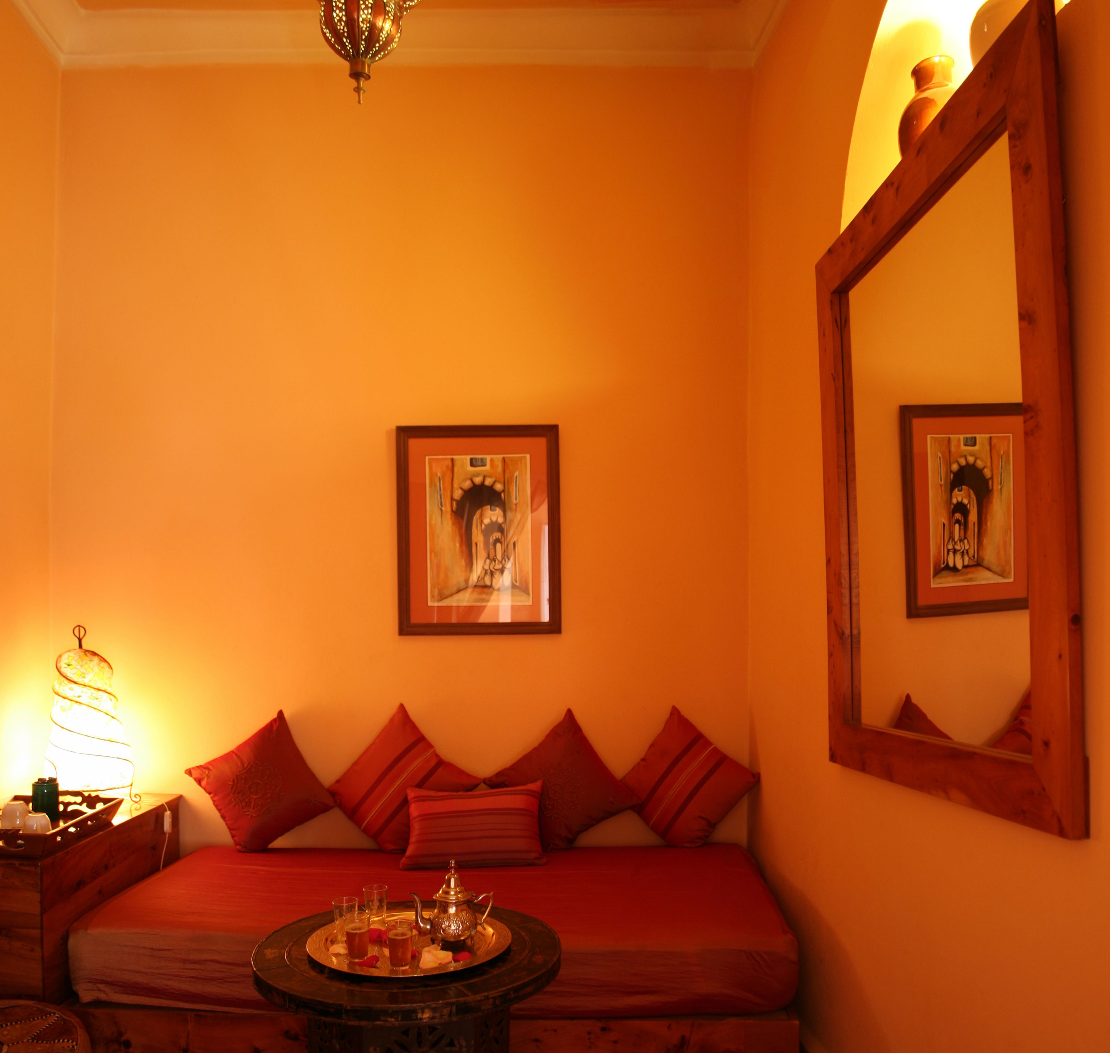A room with a bed, a table with a tray of drinks, and two framed pictures on the wall.