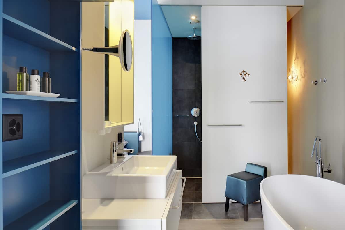 Un baño moderno con lavamanos blanco, espejo, ducha y bañera.