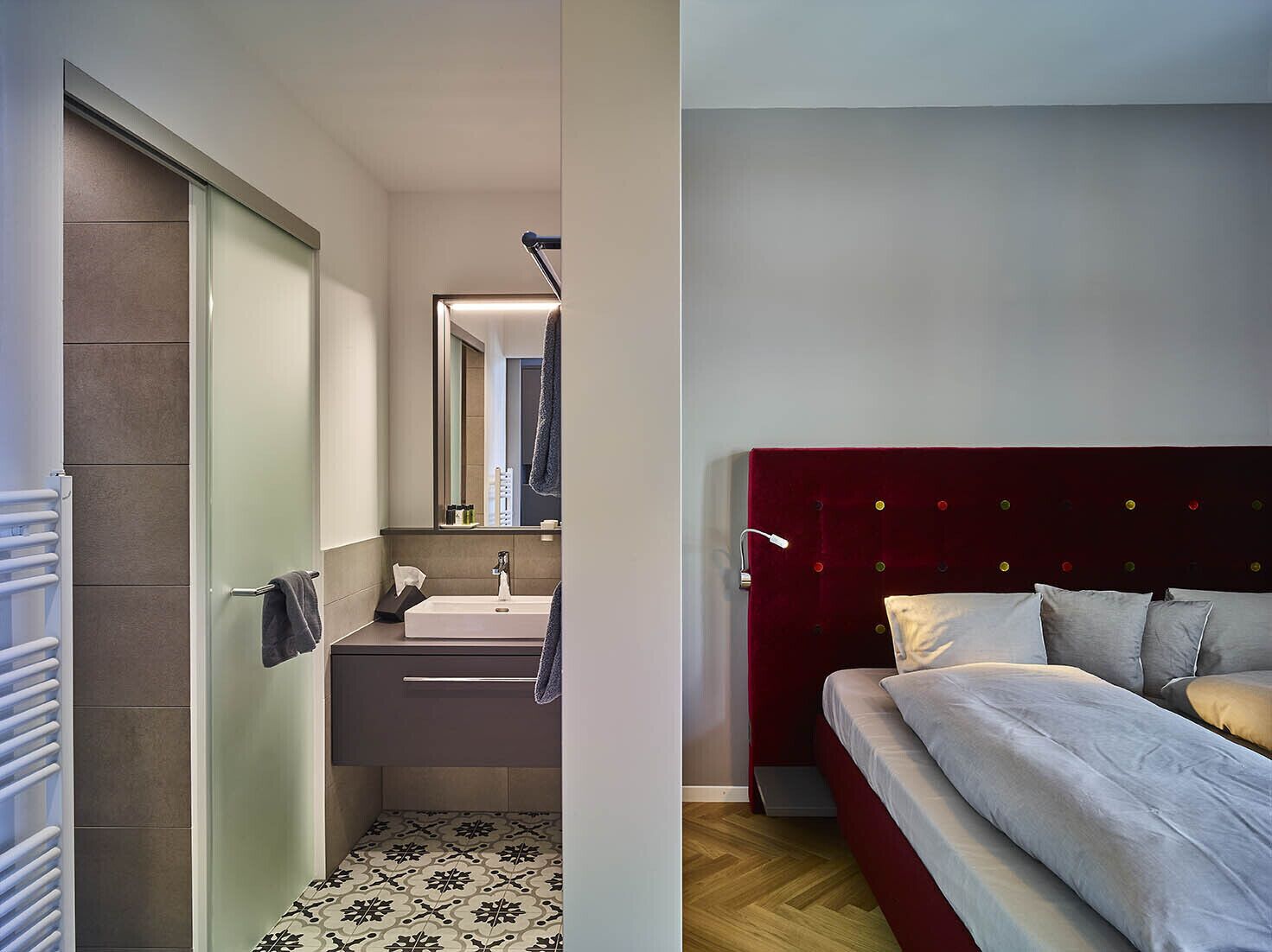 Un bagno moderno con box doccia in vetro, un lavandino bianco e uno specchio.