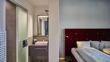Un bagno moderno con box doccia in vetro, un lavandino bianco e uno specchio.