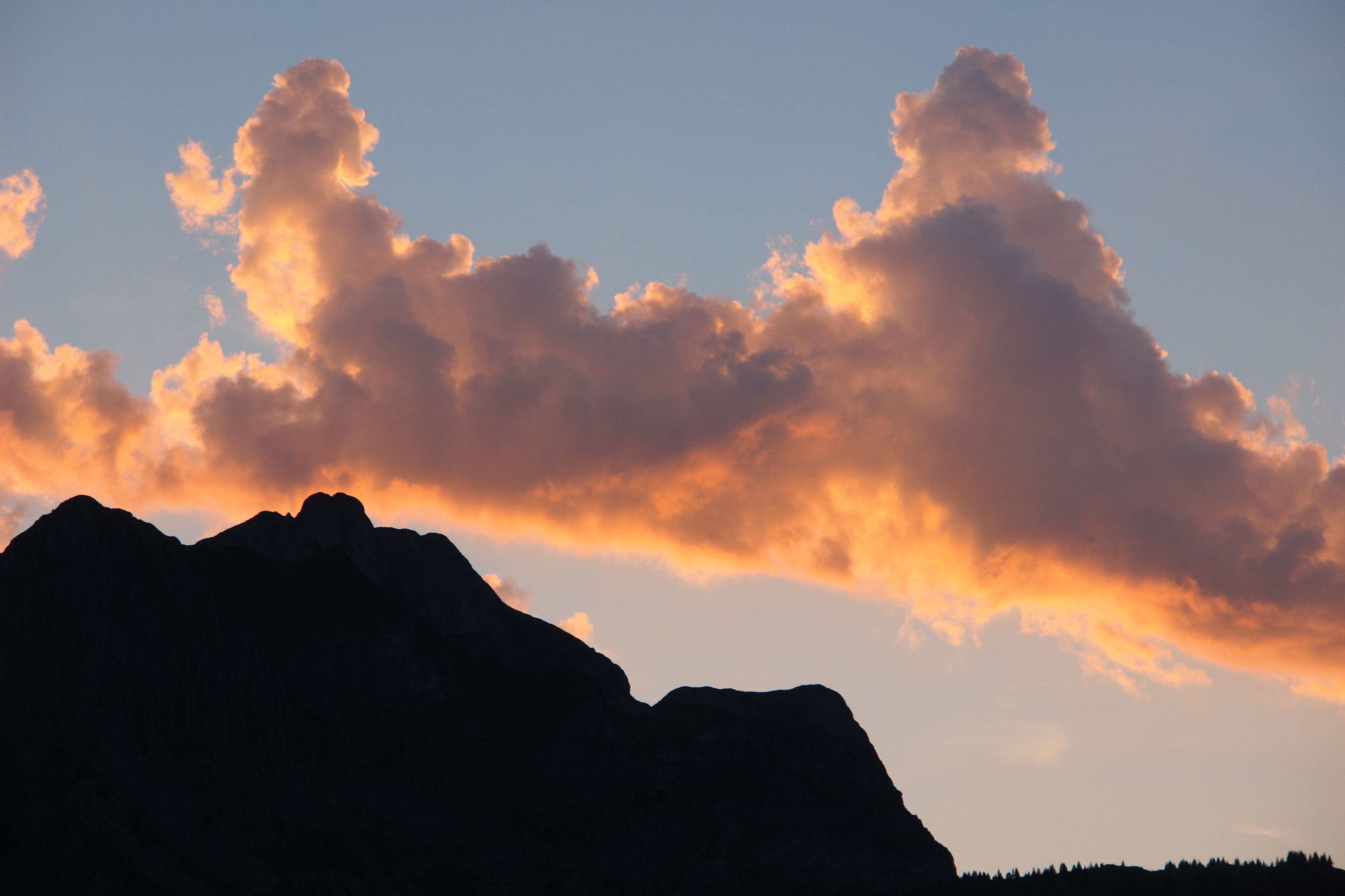 A mountain silhouette against a sunset sky.