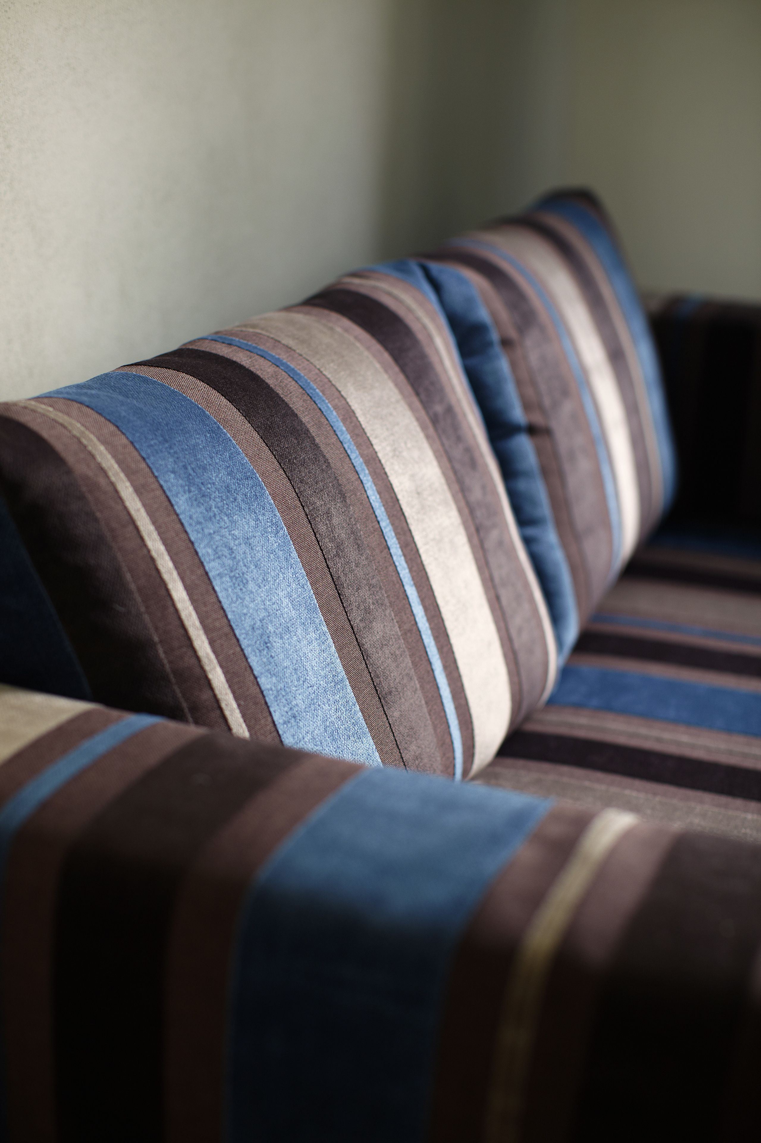 A close-up of a striped sofa with a cushion.