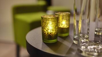 A table with three glass candle holders and a few empty glasses.