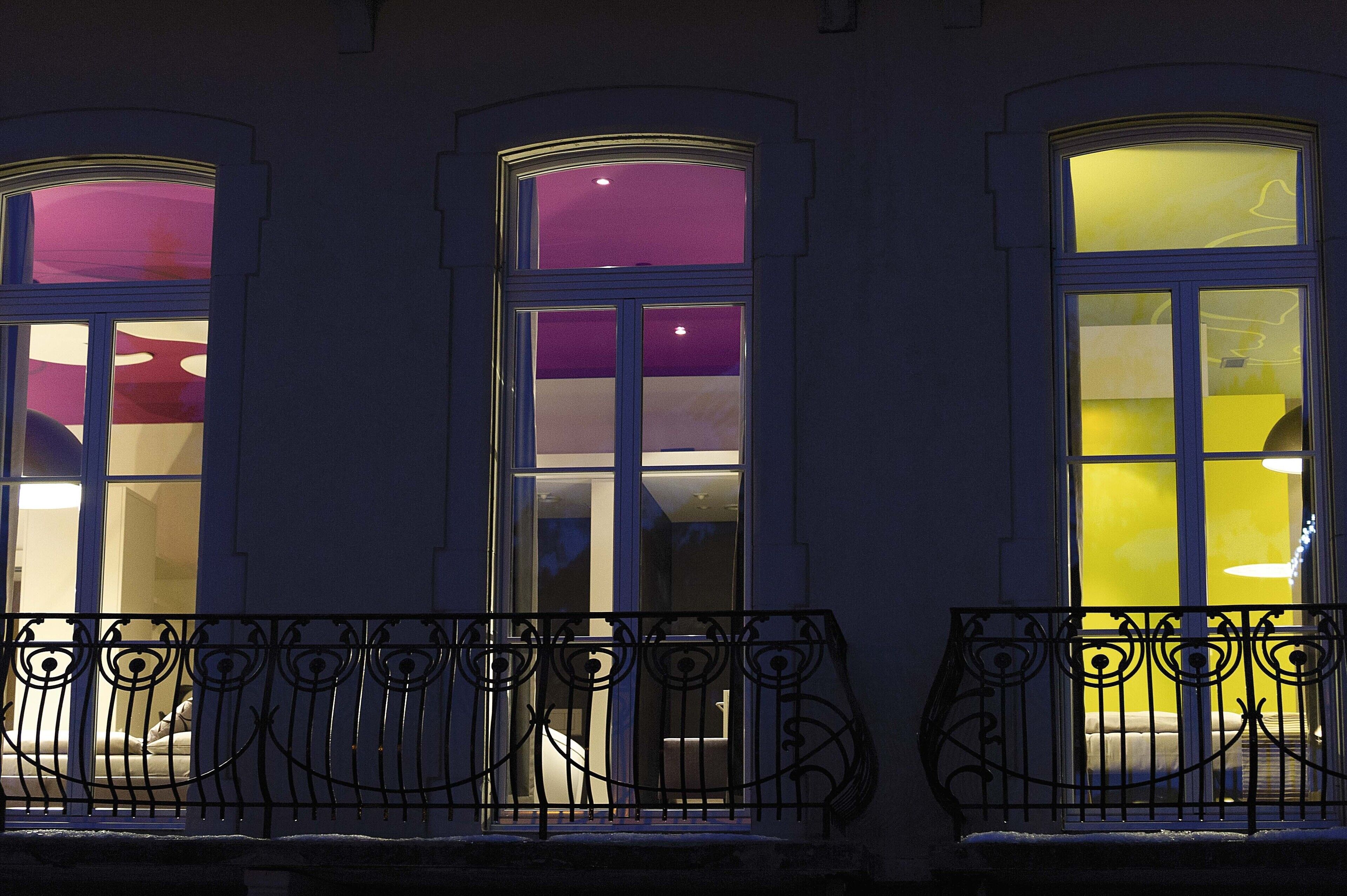Fachada de edificio con tres ventanas arqueadas, cada una con un interior de diferente color.