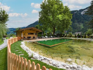 A wooden cabin with a pool, surrounded by a wooden fence, trees, and mountains in the background. - Apartments Rosenhof  (Mayrhofen)