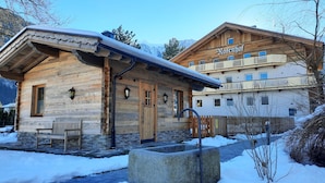 Un chalet en bois avec des fondations en pierre, un banc en bois à l’extérieur et une enseigne indiquant « Rosenhof ».