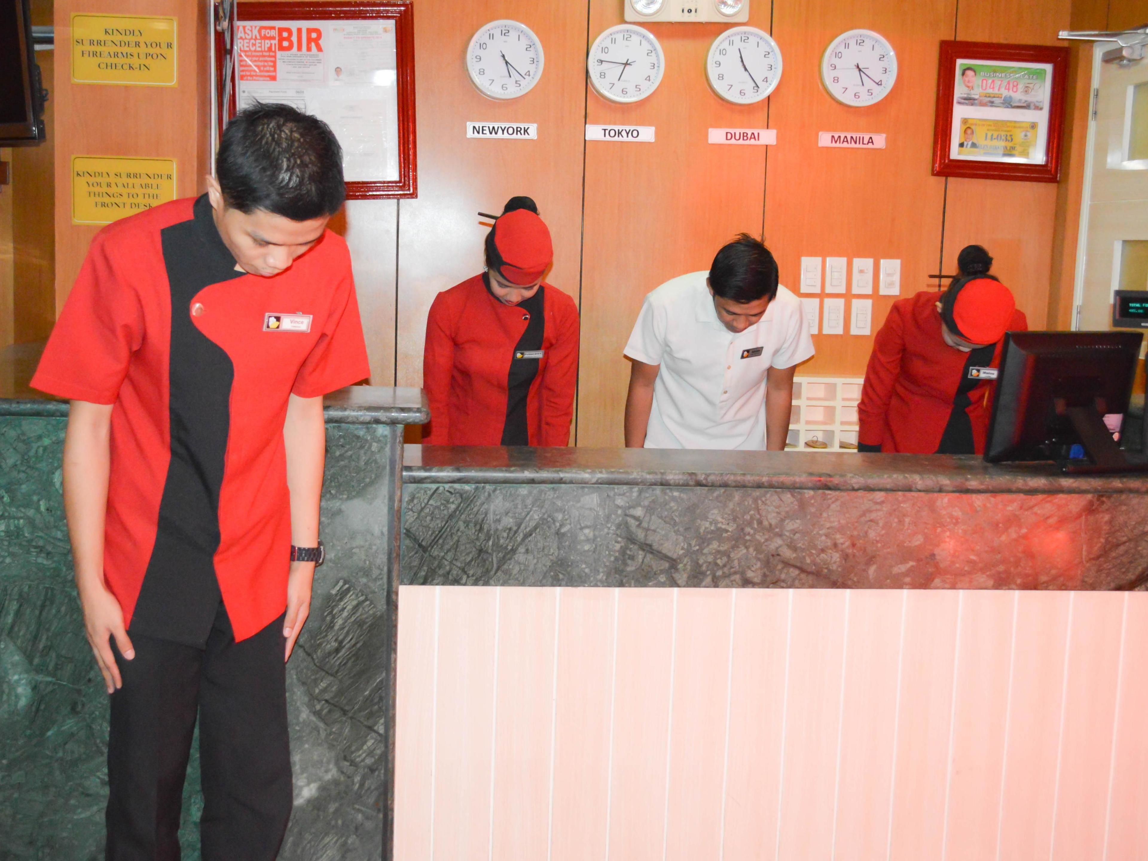 A reception desk with clocks displaying times for New York, Tokyo, Dubai, and Manila.