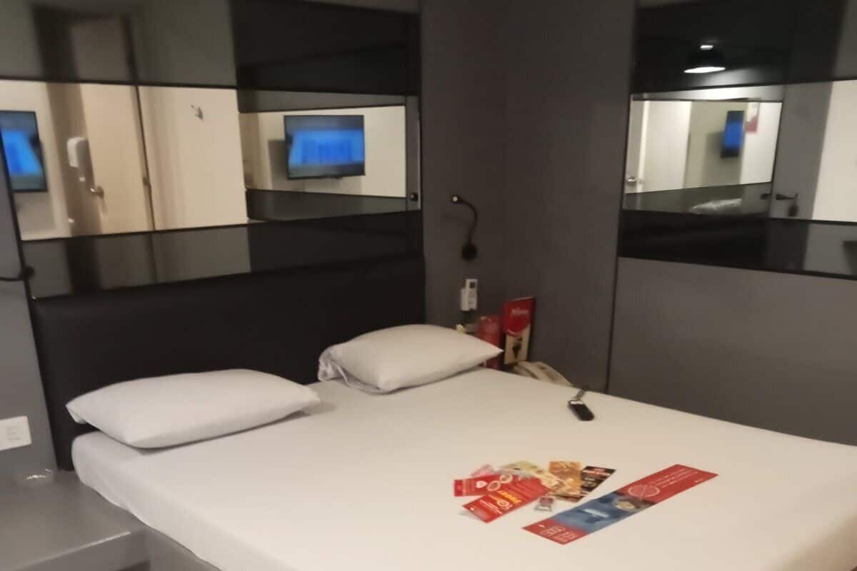 Een moderne hotelkamer met een groot bed, een nachtkastje, een spiegel en een televisie aan de muur.