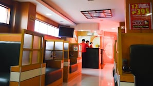 A hotel lobby with seating areas, a reception desk, and a promotional sign for a 12-hour premium room rate.