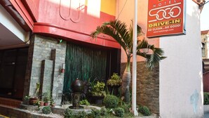 A hotel entrance with a red awning, a stone facade, and a drive-in sign.