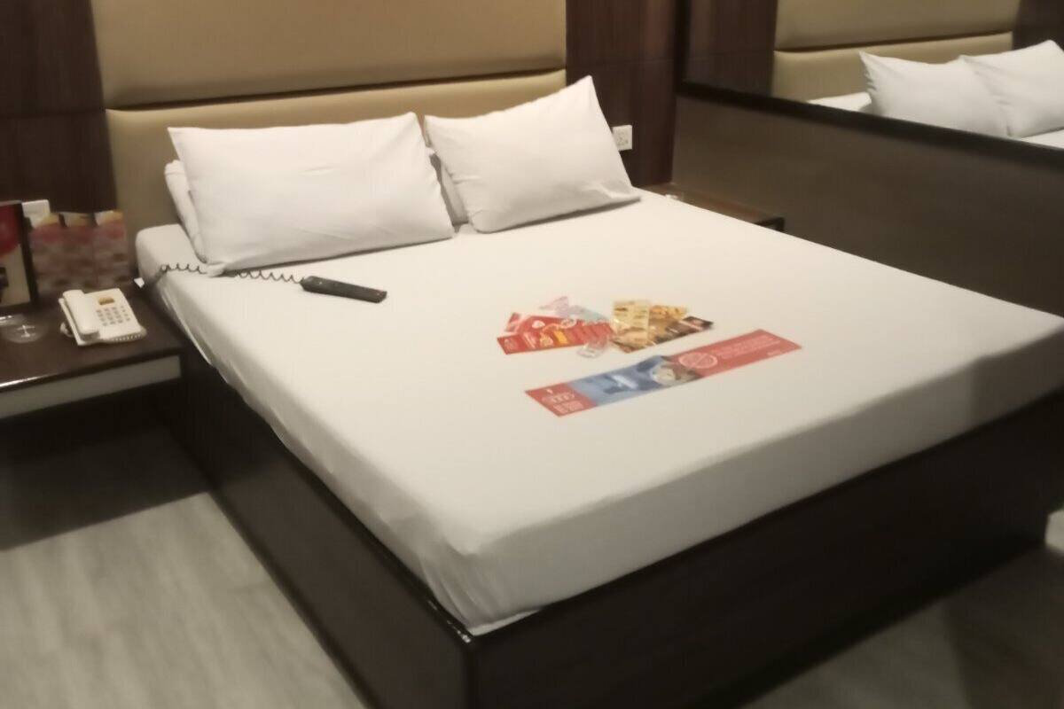Een hotelkamer met een bed, een nachtkastje met telefoon en een spiegel aan de muur.
