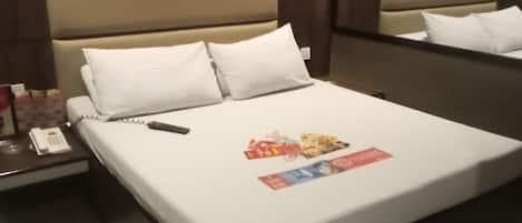 A hotel room with a bed, a bedside table with a phone, and a mirror on the wall.