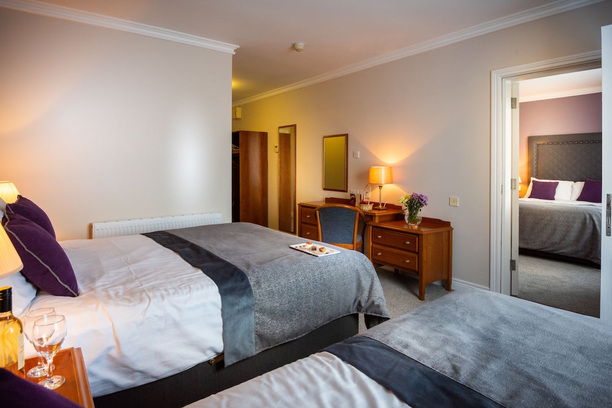 Habitación de hotel con dos camas, un escritorio y un espejo.