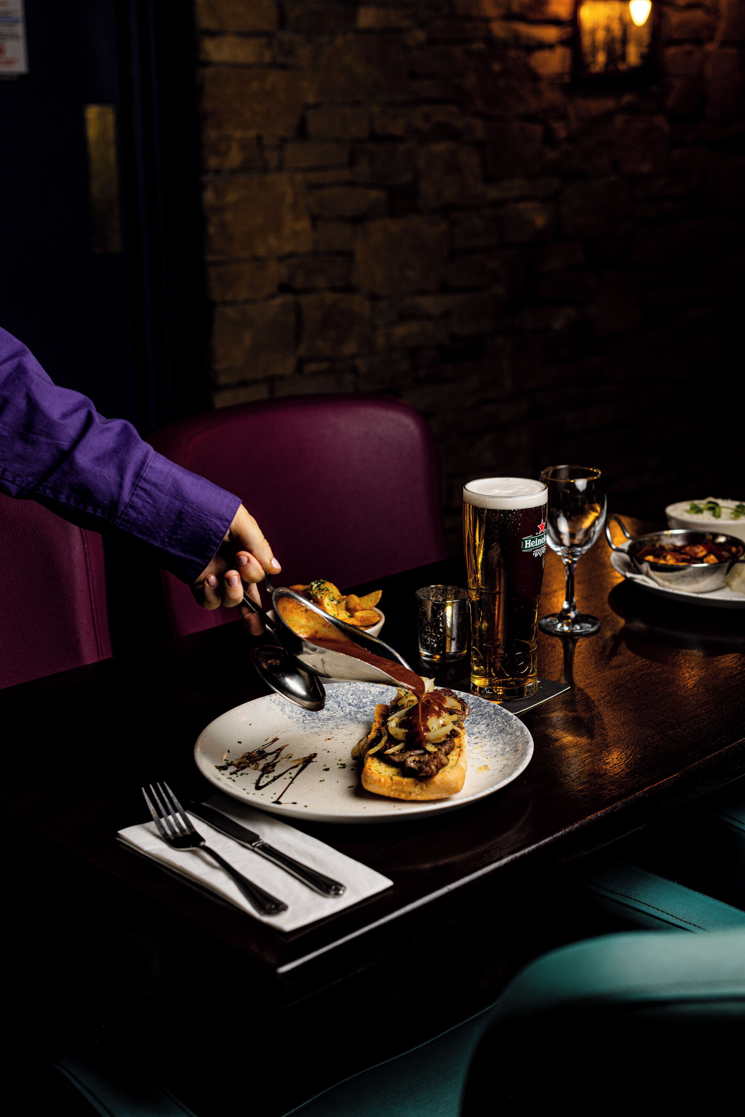 A dining table with a plate of food, a beer glass, and a wine glass.
