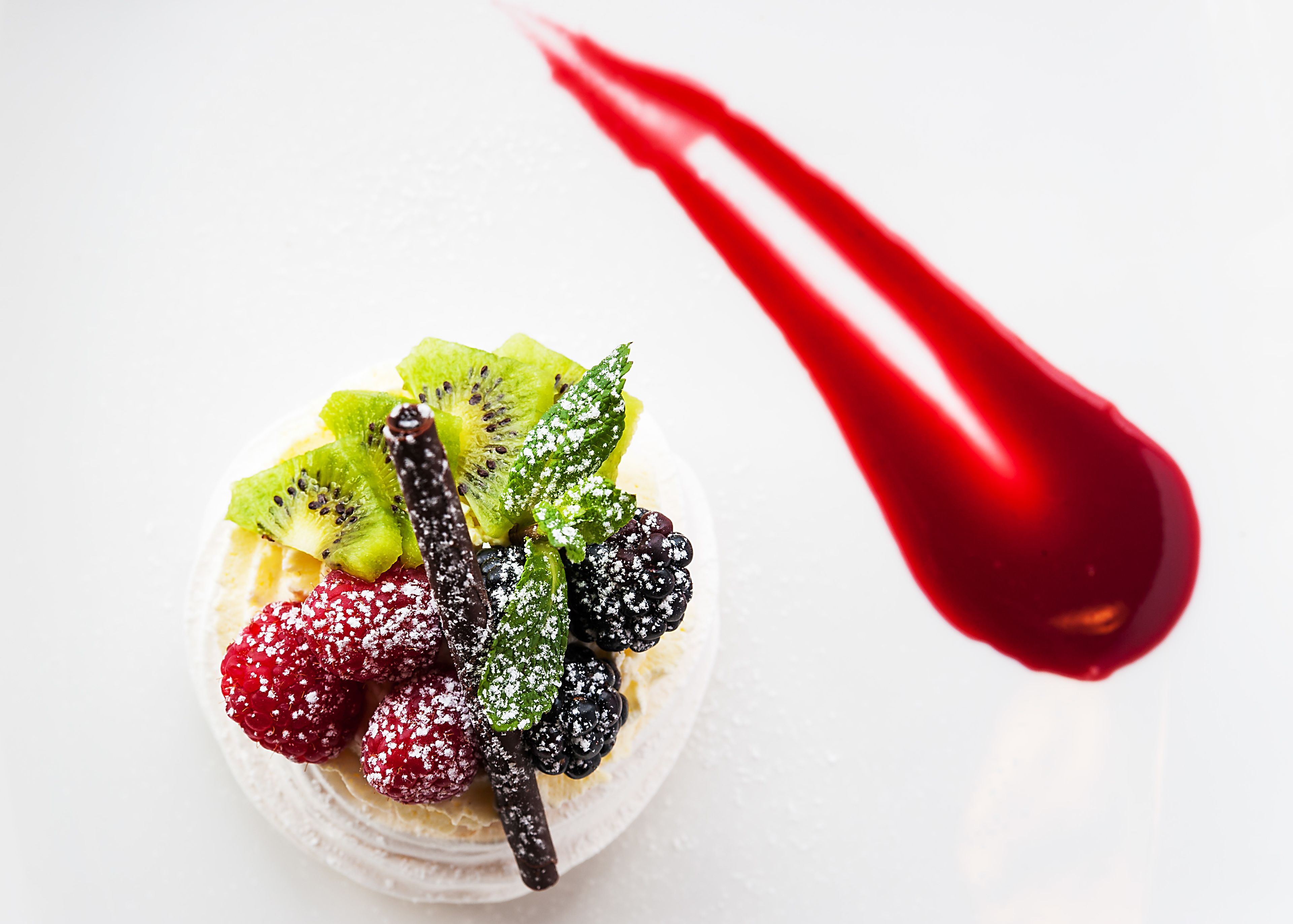 A dessert with various fruits and a red spoon.