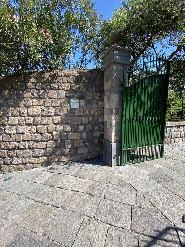 A stone wall with a green gate, a stone pavement, and a sign with the number 11. - Chalet Lidia (Sorrento)