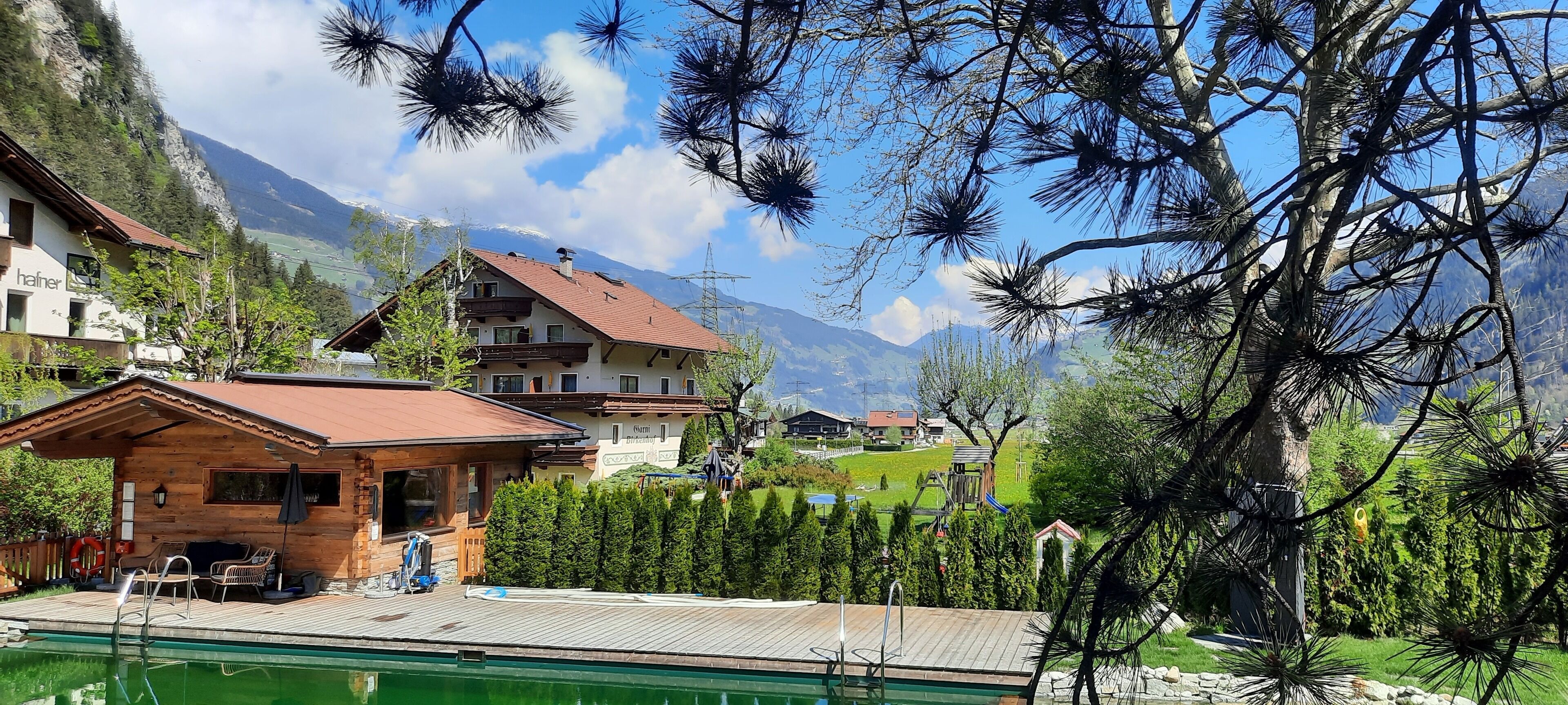 A mountain lodge with a pool, wooden deck, and mountain views.