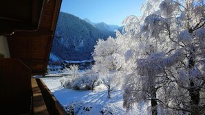 A snowy mountain landscape with a building in the foreground.