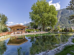 A wooden cabin with a pool, surrounded by trees and mountains. - Gästehaus Birkenhof (Mayrhofen)
