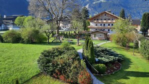 A hotel with a garden, a playground, and a mountain backdrop.