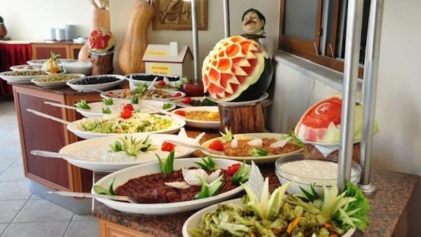 A buffet with various dishes and a decorative watermelon centerpiece. - Inside Hotel (Manavgat)
