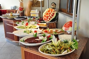 A buffet with various dishes and a decorative watermelon centerpiece. - Inside Hotel (Manavgat)